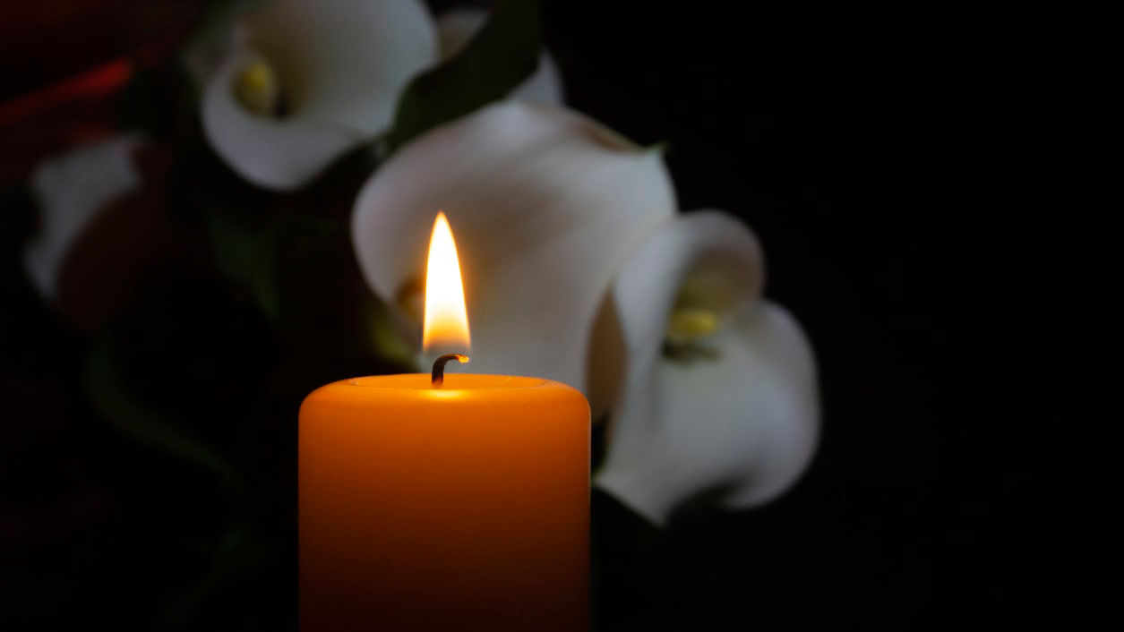 Calla lilies and a candle on a dark background.