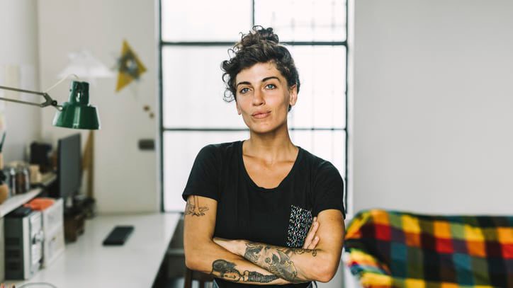 A woman with tattoos standing in her home office.