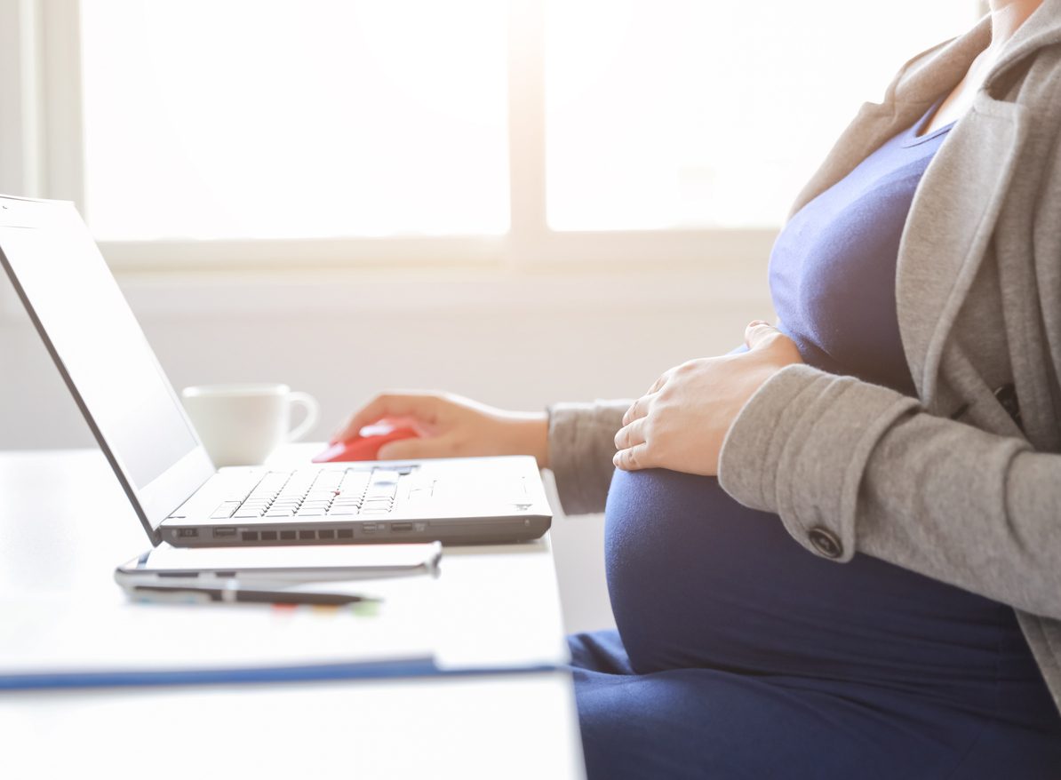 A pregnant worker at her laptop.