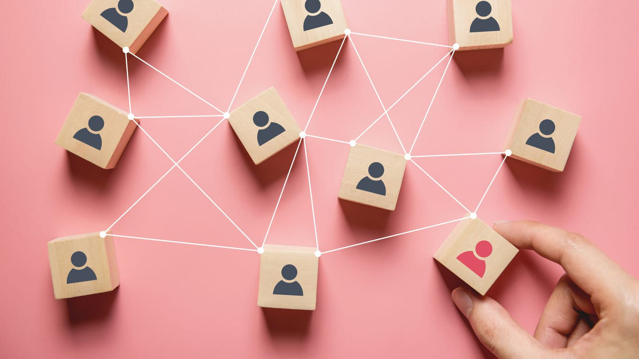 A hand holding a set of wooden cubes with people on them.