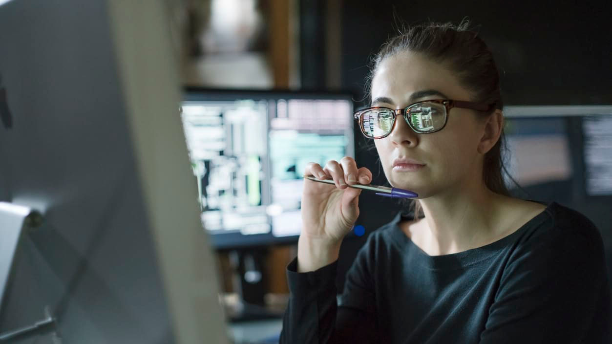 A woman in glasses sitting in front of a computer.