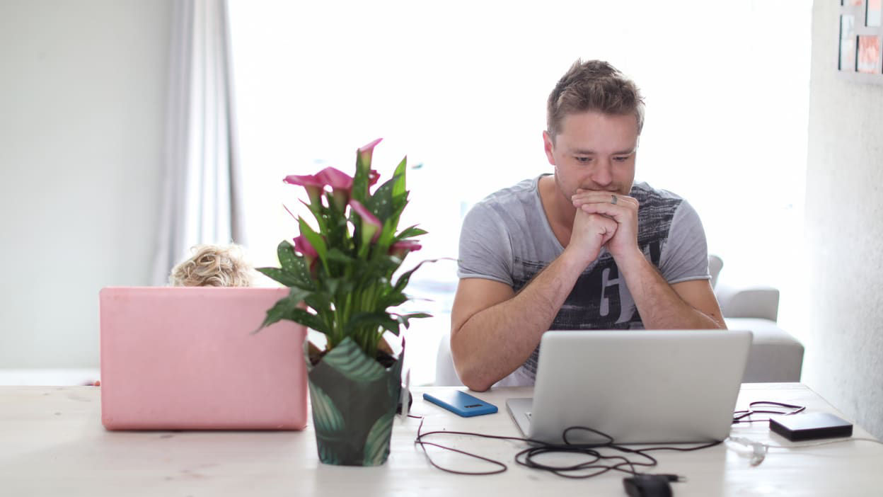 A man and woman sitting at a table with a laptop.