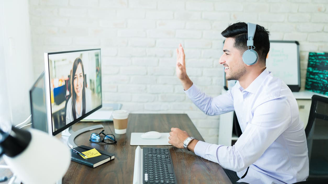 A man is on a video call with a woman at his desk.