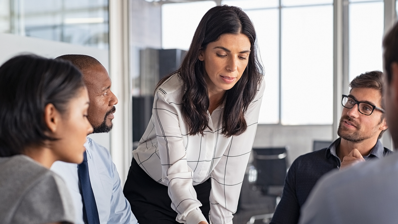 Team of multiethnic architects working on construction plans in meeting room. Engineers and designers discussing project in office. Businesswoman with business team in conference room working on blueprint.