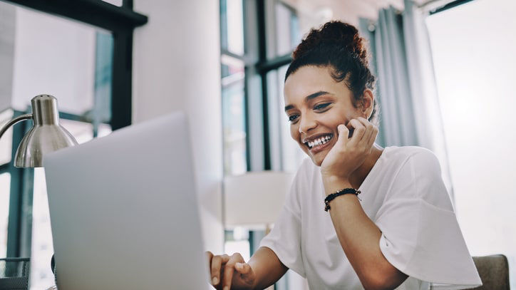 A woman is talking on the phone while working on her laptop.