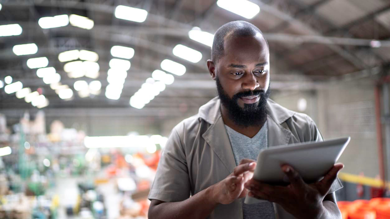 A man using a tablet in a warehouse.