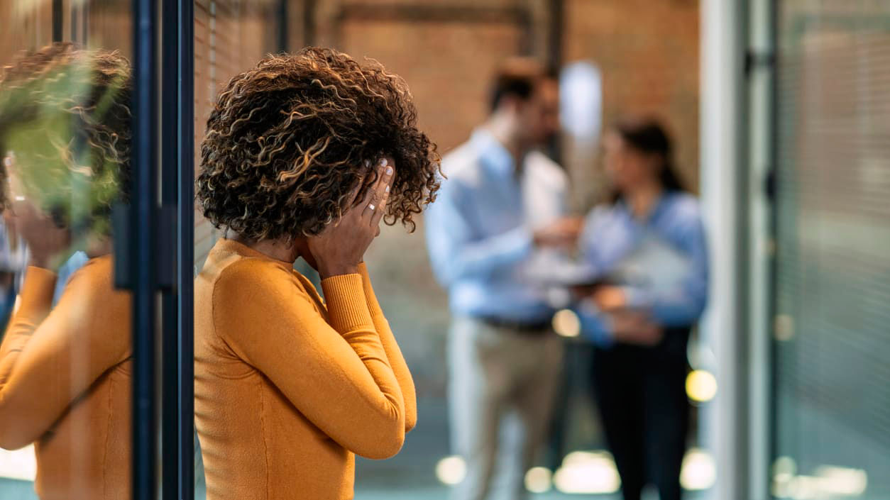 A woman is standing in front of a glass door in an office.