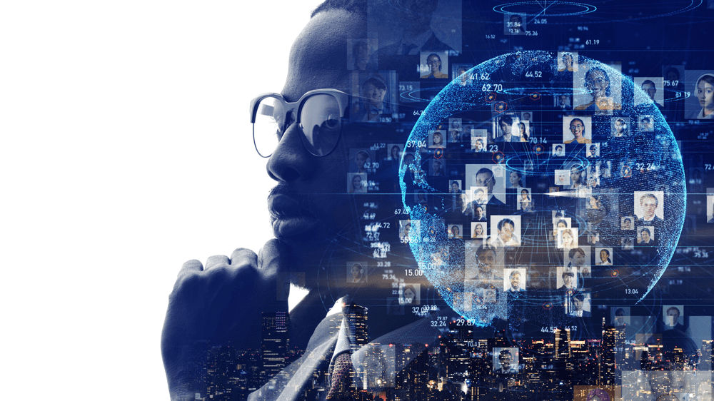 A man in glasses is looking at a globe with many people in it.