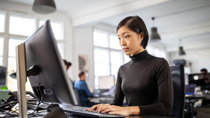 A woman working on a computer in an office.
