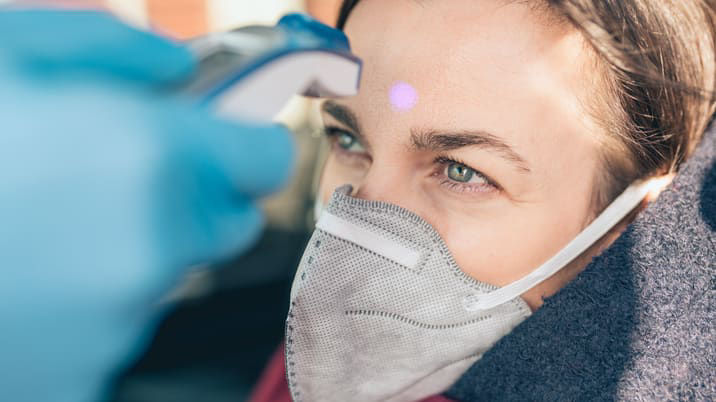 A woman is wearing a face mask in a car.