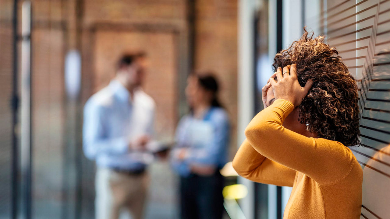 A woman is holding her head up in front of a group of people in an office.