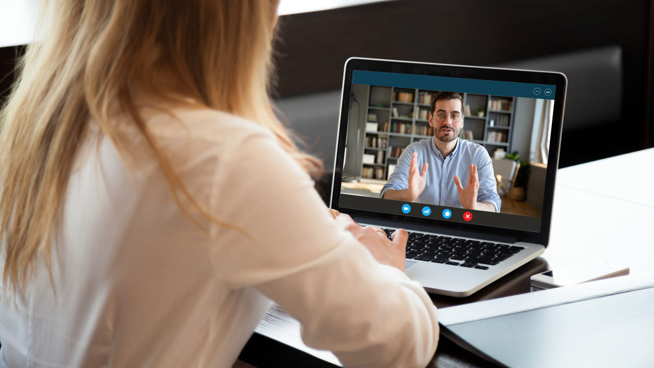 A woman is watching a video on her laptop.