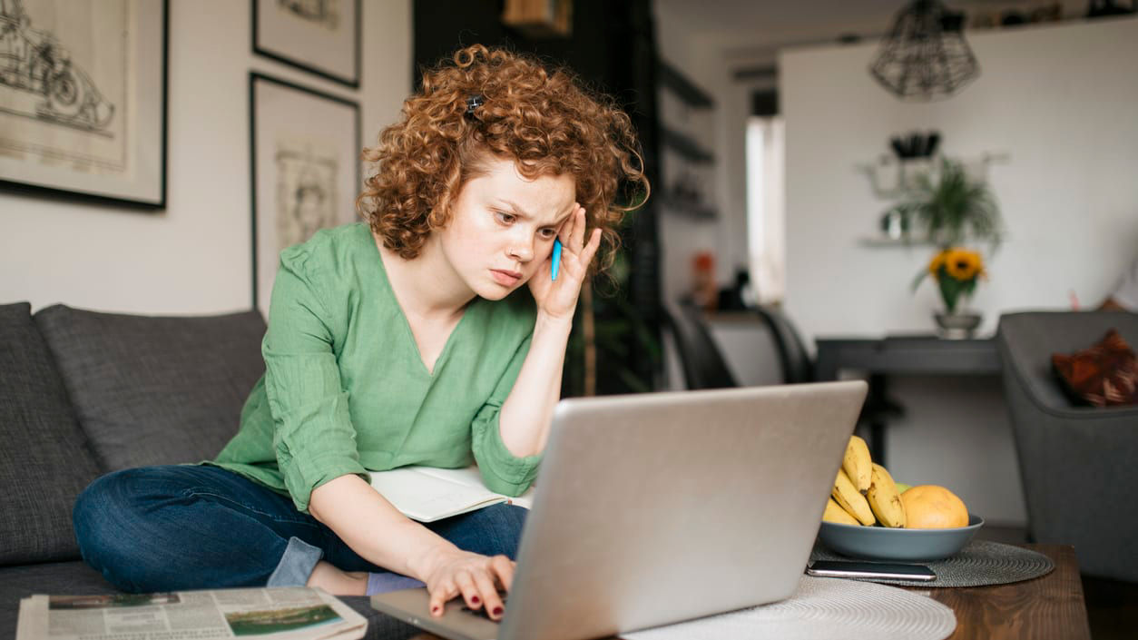 A woman sitting on a couch with a laptop on her lap.