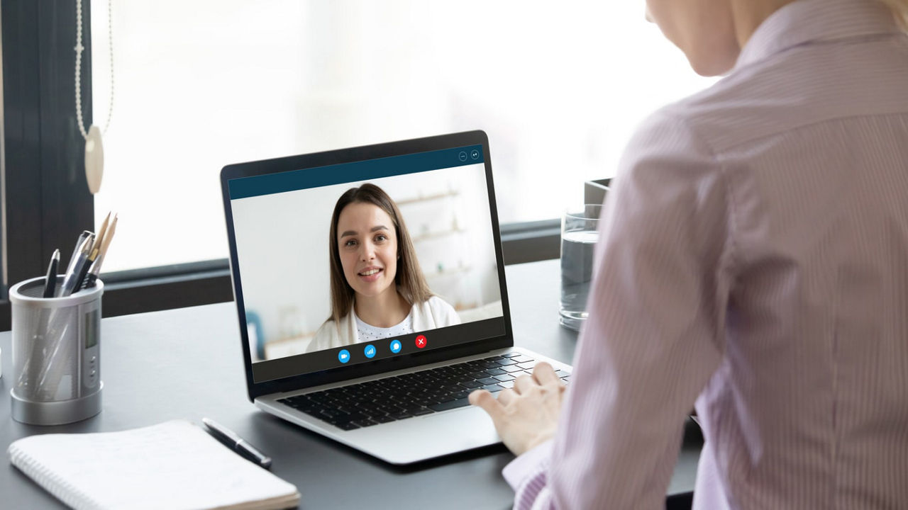 A woman is using a laptop to make a video call.