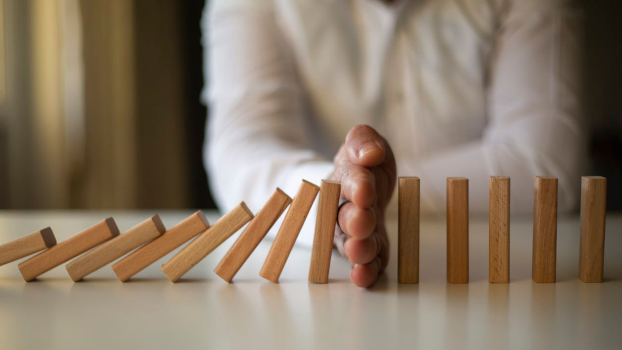 A man is holding a wooden domino on a table.