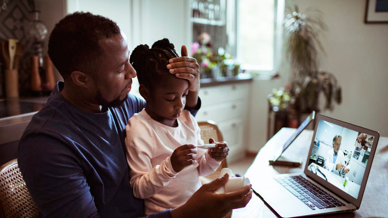 A man and his daughter are watching a video on a laptop.
