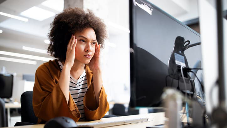 A woman with afro hair is looking at her computer screen.