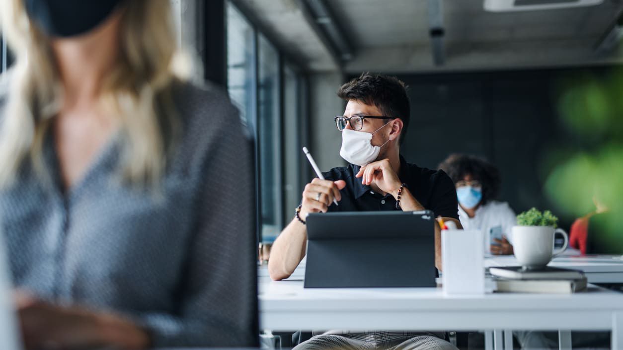 A group of people wearing face masks in an office.