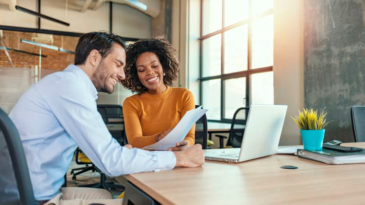 Two business people looking at a laptop in an office.