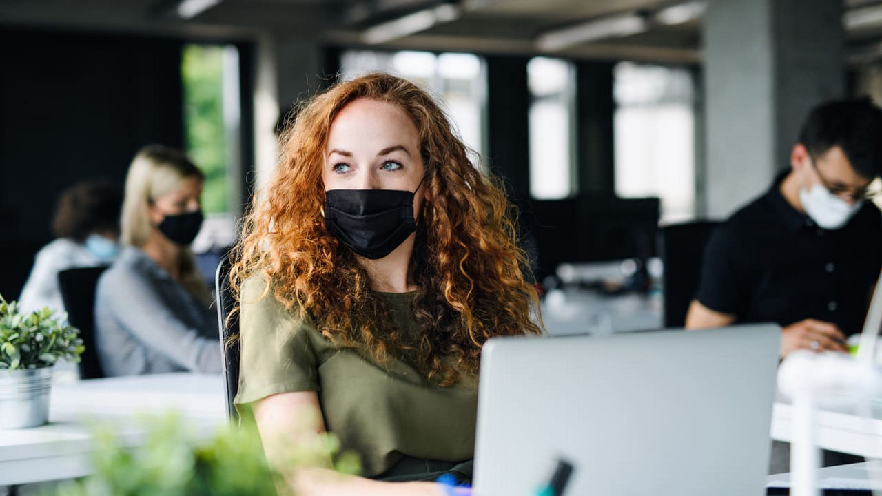 A woman wearing a face mask in an office.