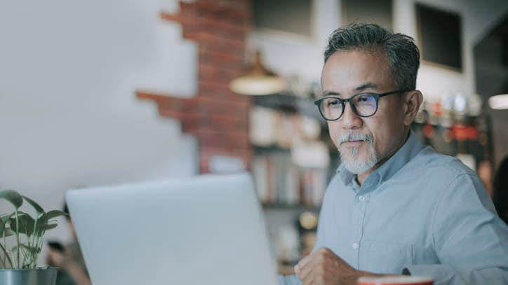 An man working on a laptop in a coffee shop.