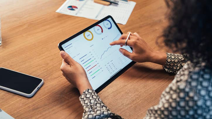 A woman using an ipad on a wooden table.