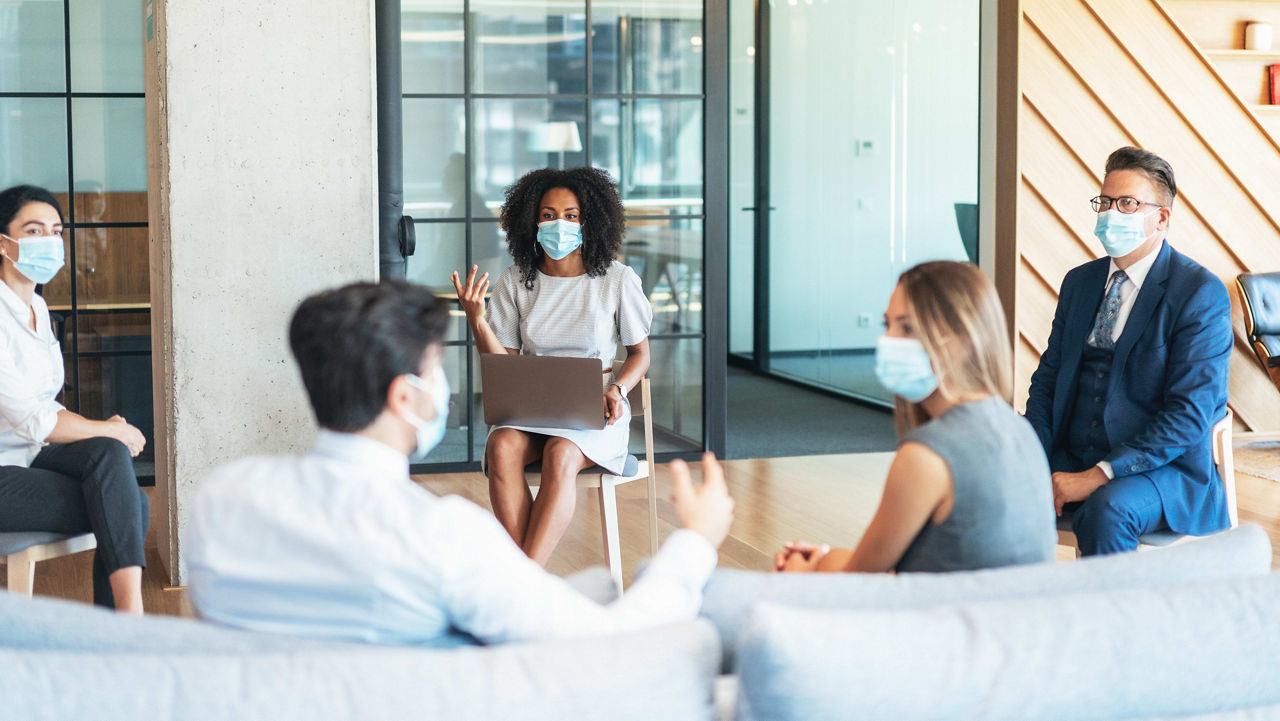 A group of people wearing face masks in an office.