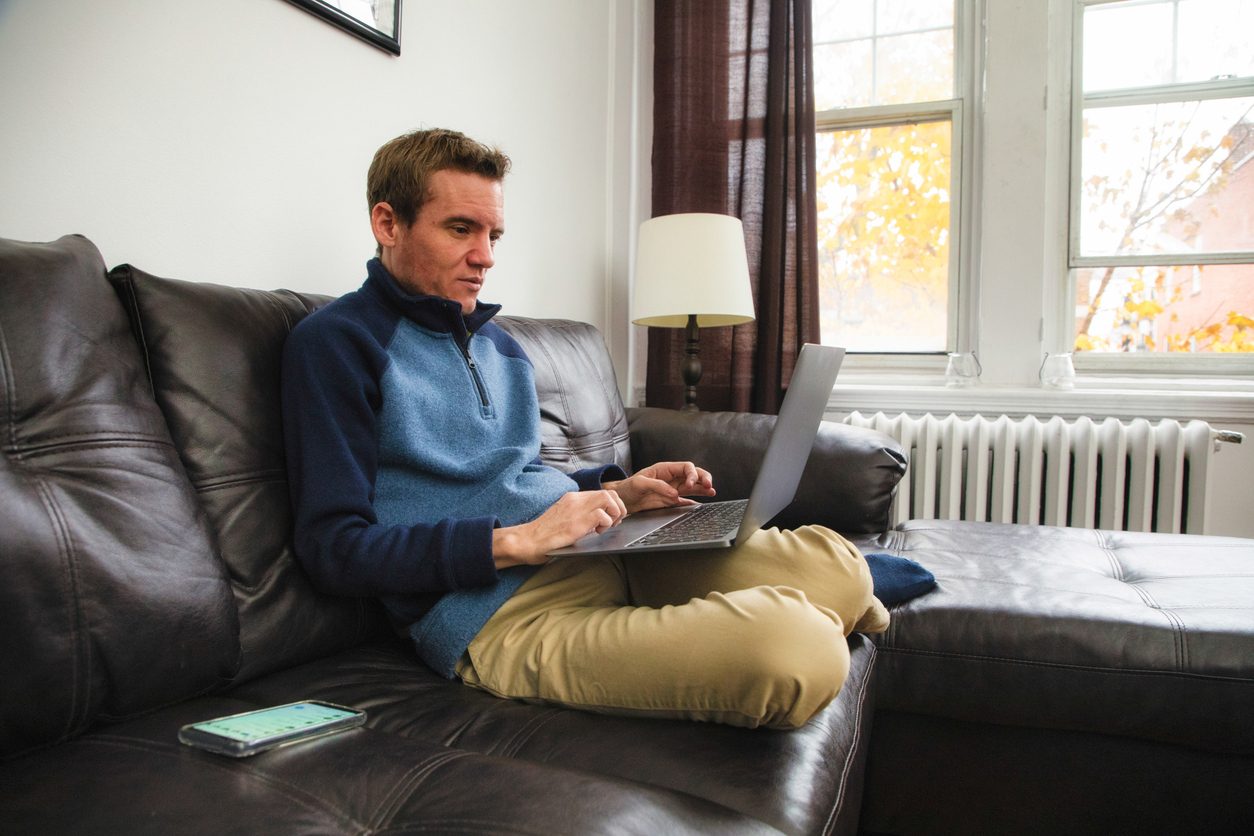 Autistic employee works on laptop while sitting on leather couch