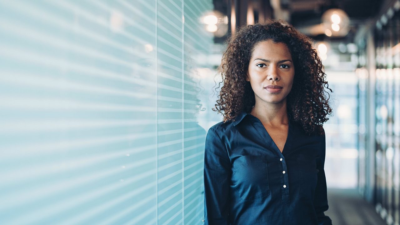 A business woman standing in front of a glass wall.