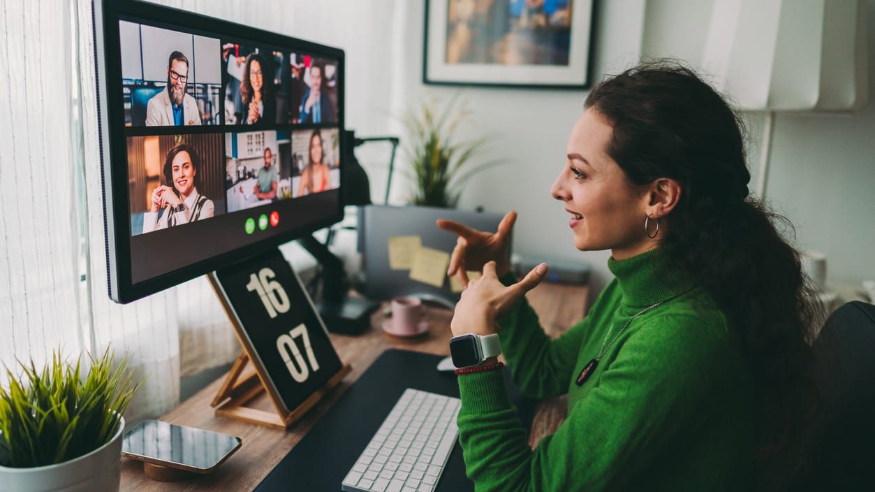 A woman in a green sweater is looking at a computer screen.