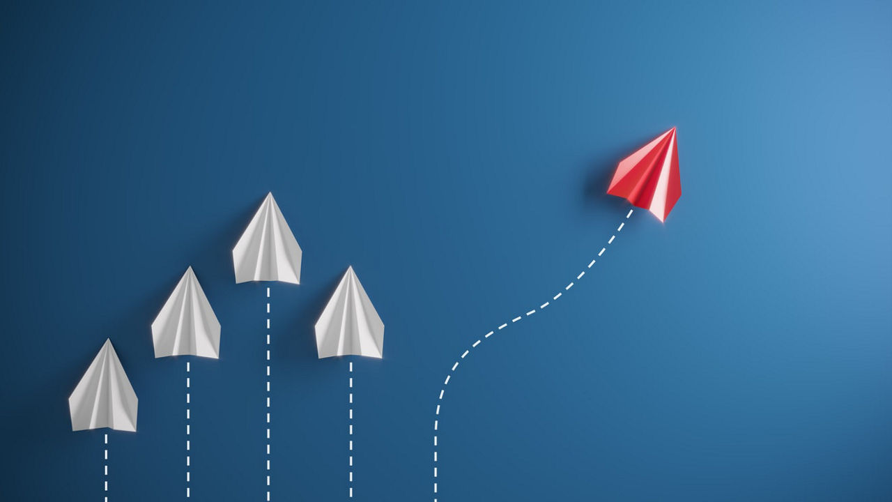 A group of red paper planes flying in the direction of a blue background.