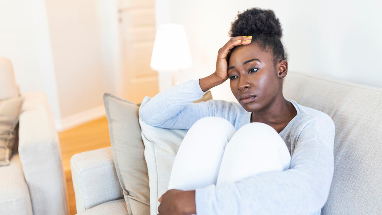 A woman sitting on a couch with her head on her head.