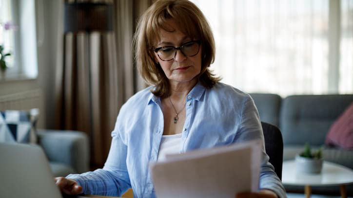 A woman sitting at a table with a laptop and papers.