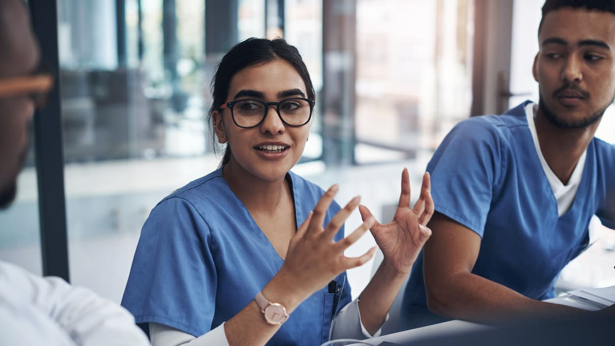 A group of nurses in scrubs sitting at a table.