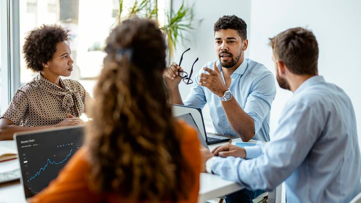 A group of people sitting around a table in an office.