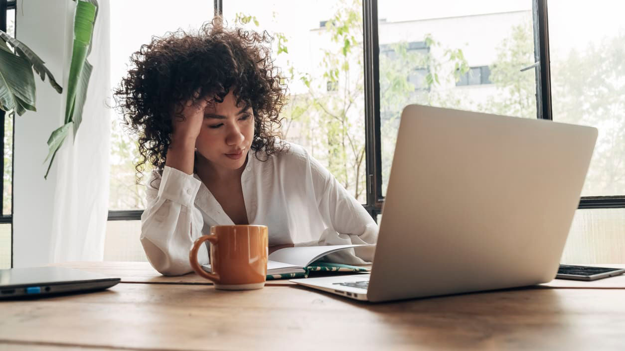 A woman sitting at a desk with a laptop and a cup of coffee.