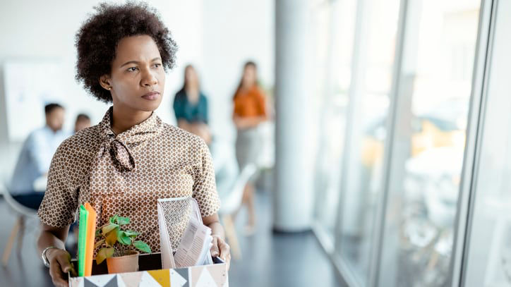 A woman carrying a paper bag in an office.