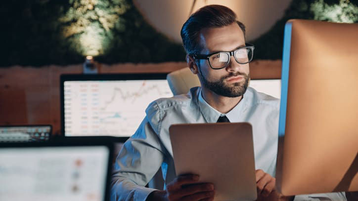 A man sitting at a desk looking at a computer screen.