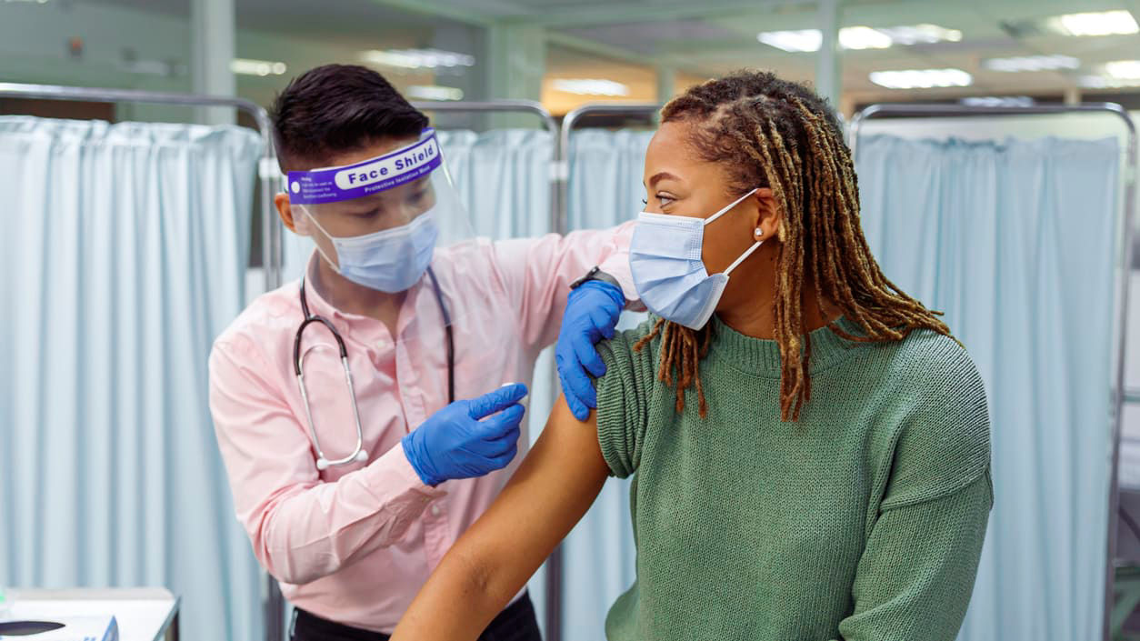 A man is giving a woman a vaccine in a hospital.
