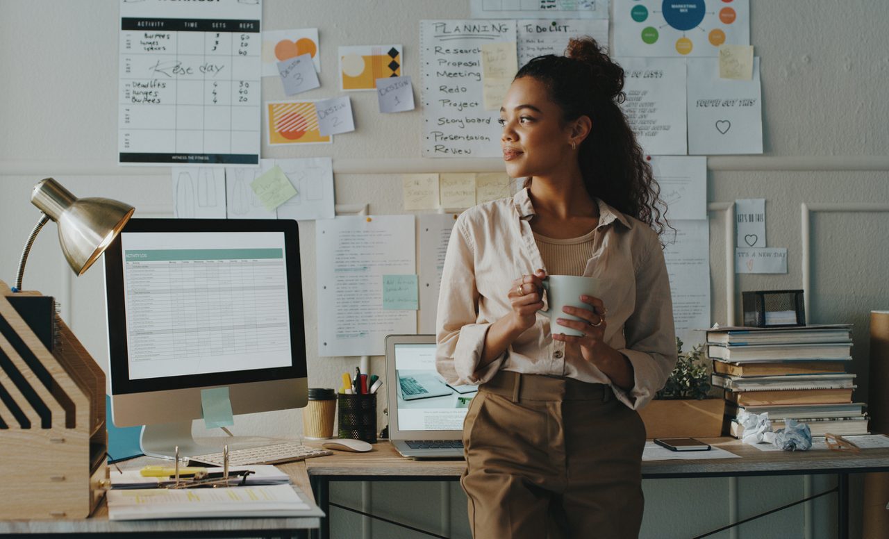 woman holds coffee in her office