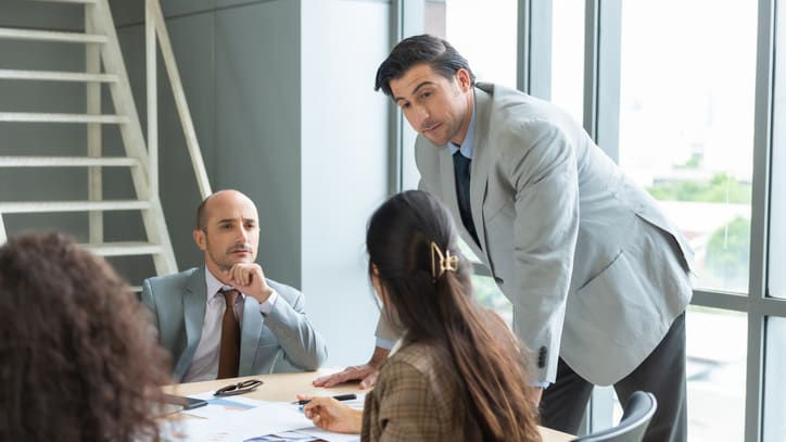 A group of business people sitting around a table in an office.