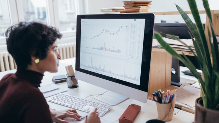 A woman sitting at a desk looking at a computer screen.