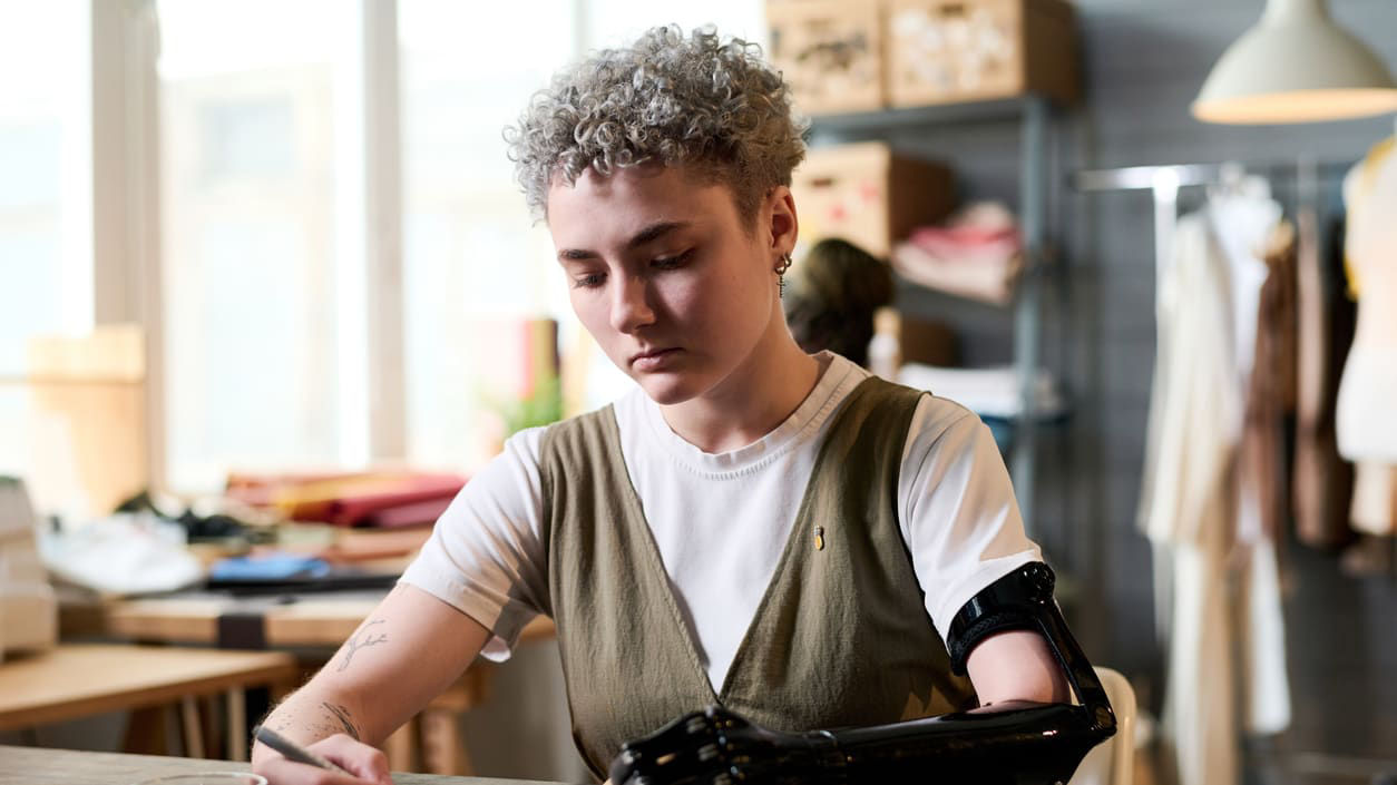 A woman is working at a desk with a robotic arm.