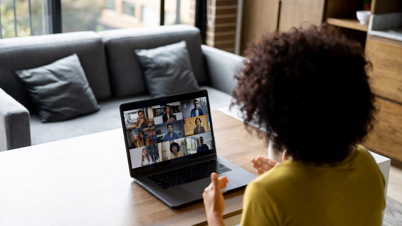 A woman is sitting at a table and using a laptop.