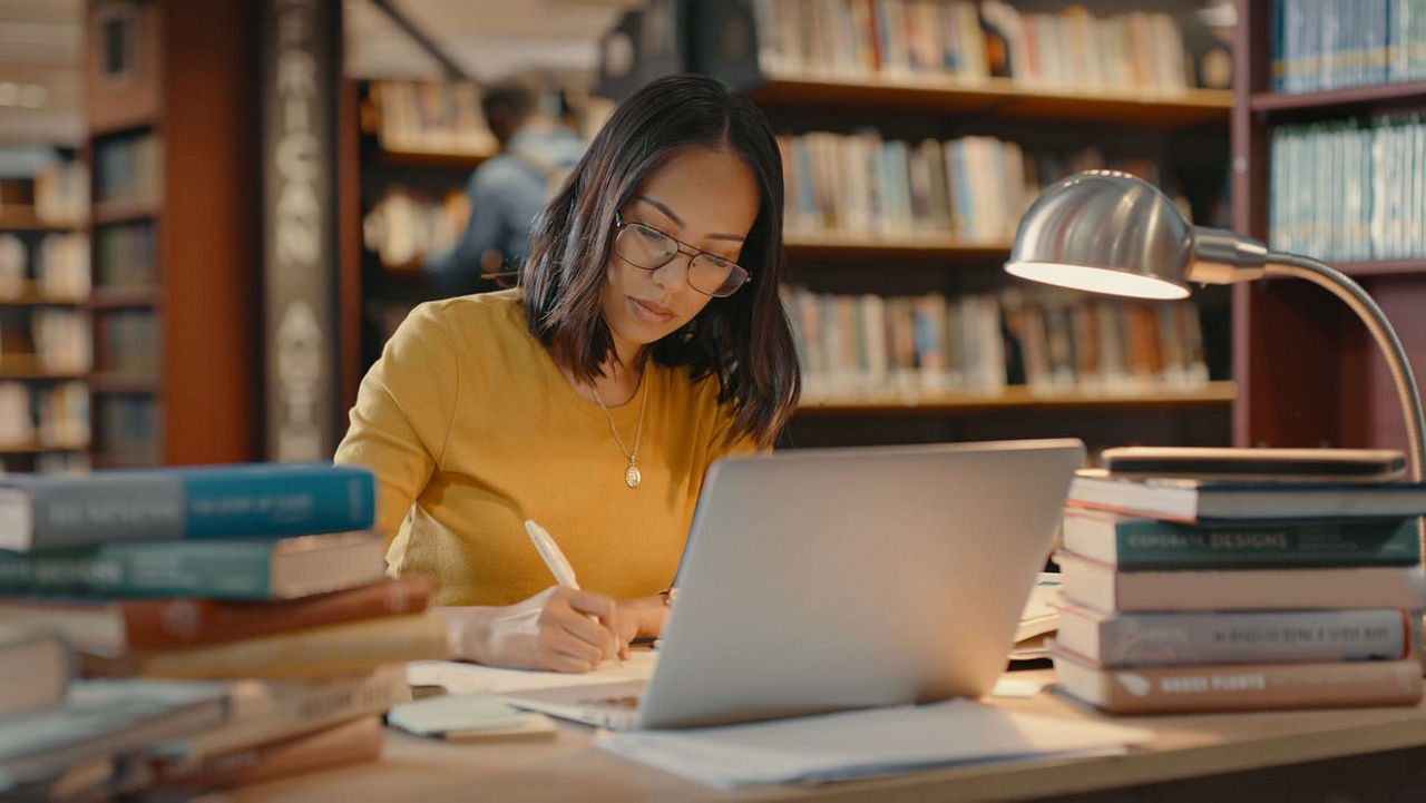 A woman working on her laptop in a library.