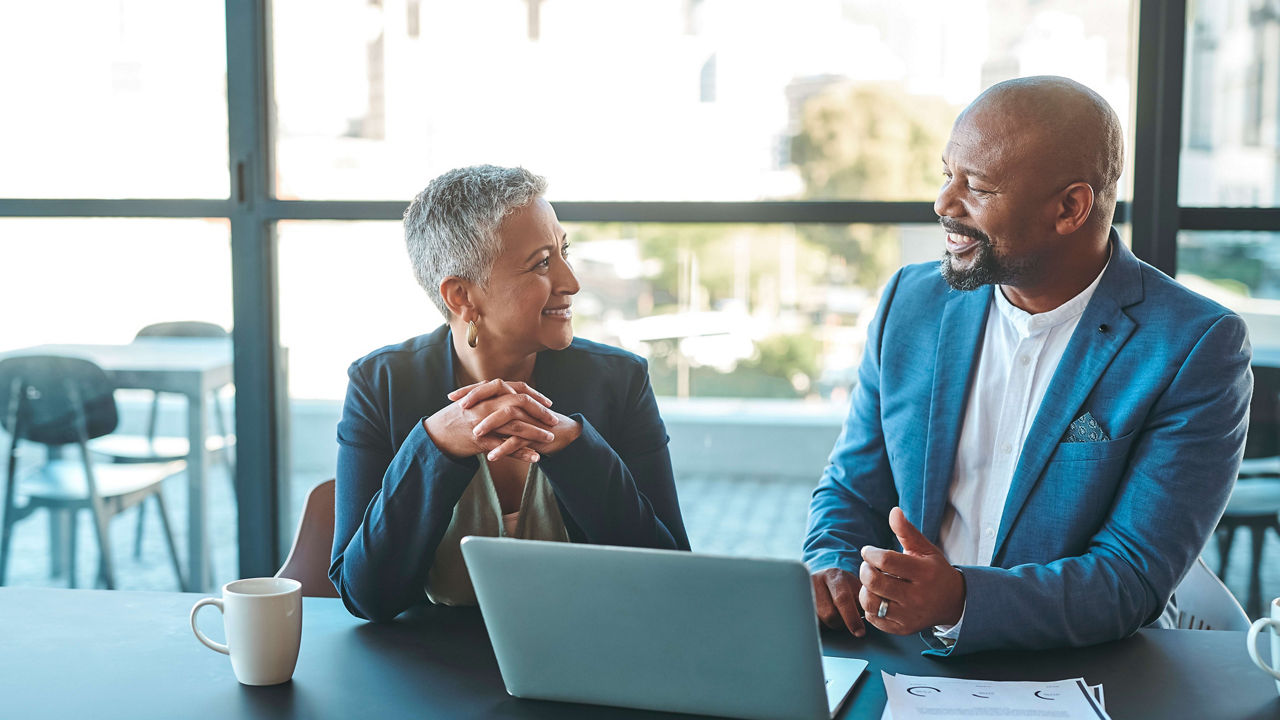Two business people talking at a conference table.
