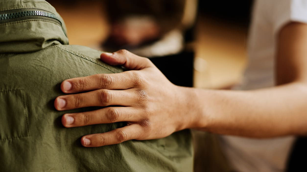 A person puts their hand on another person's shoulder.