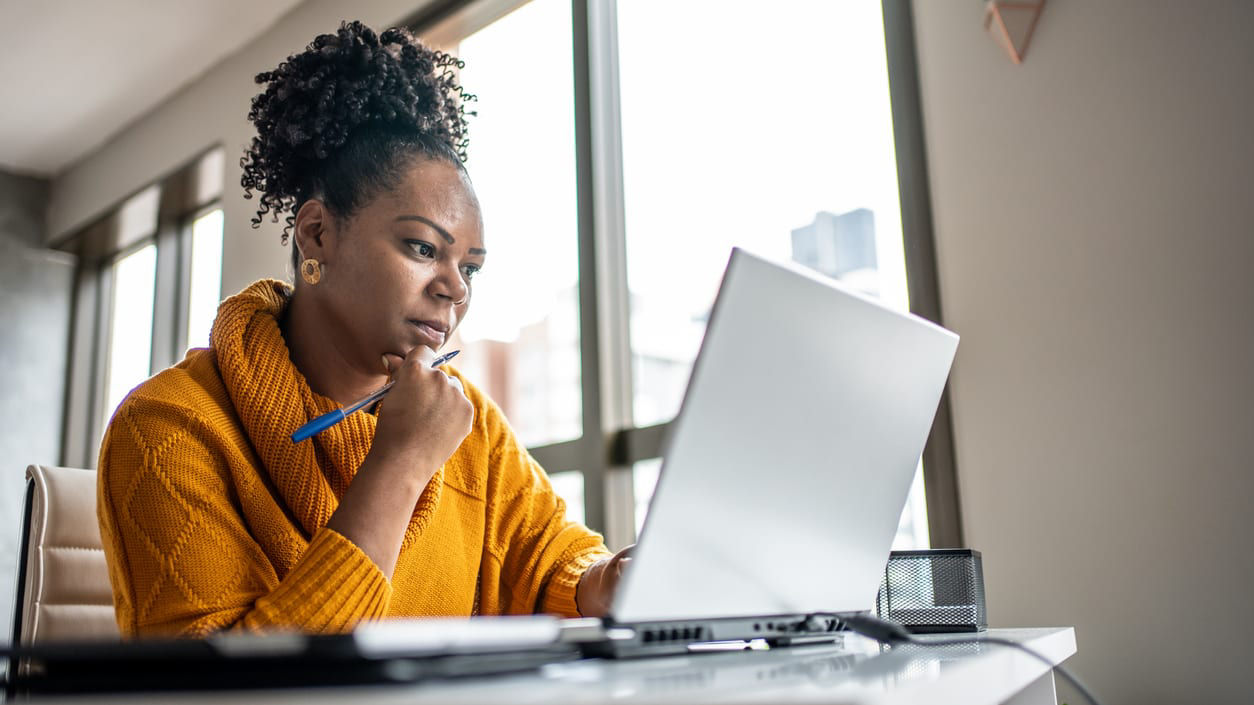 A woman working on a laptop in front of a window.