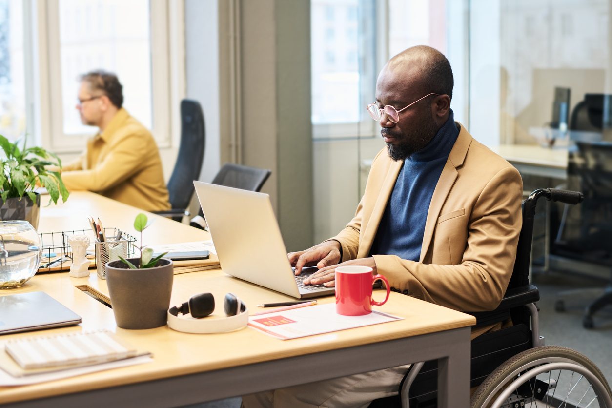 Black man in wheelchair on computer at work