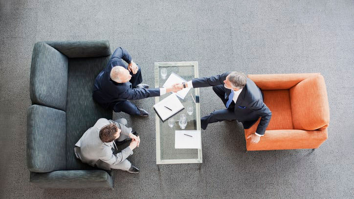 Three businessmen shaking hands at a table.